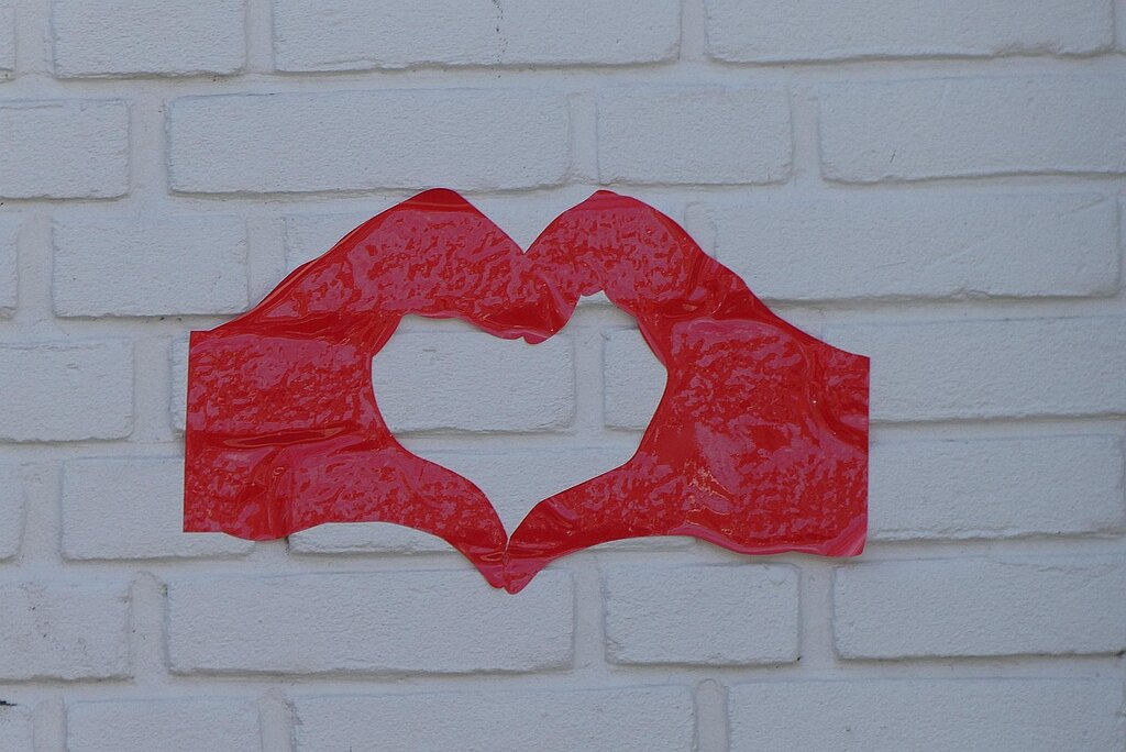 Grafitiy zwei rote Hände zum Herz geformt